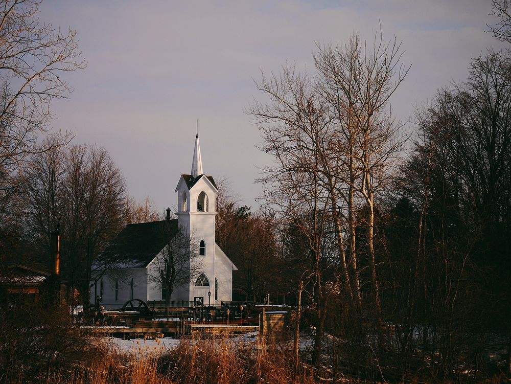 A small white church surrounded by trees. Original public domain image from Wikimedia Commons