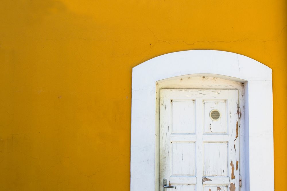 Yellow wall and a white door in Kapolcs, Hungary. Original public domain image from Wikimedia Commons