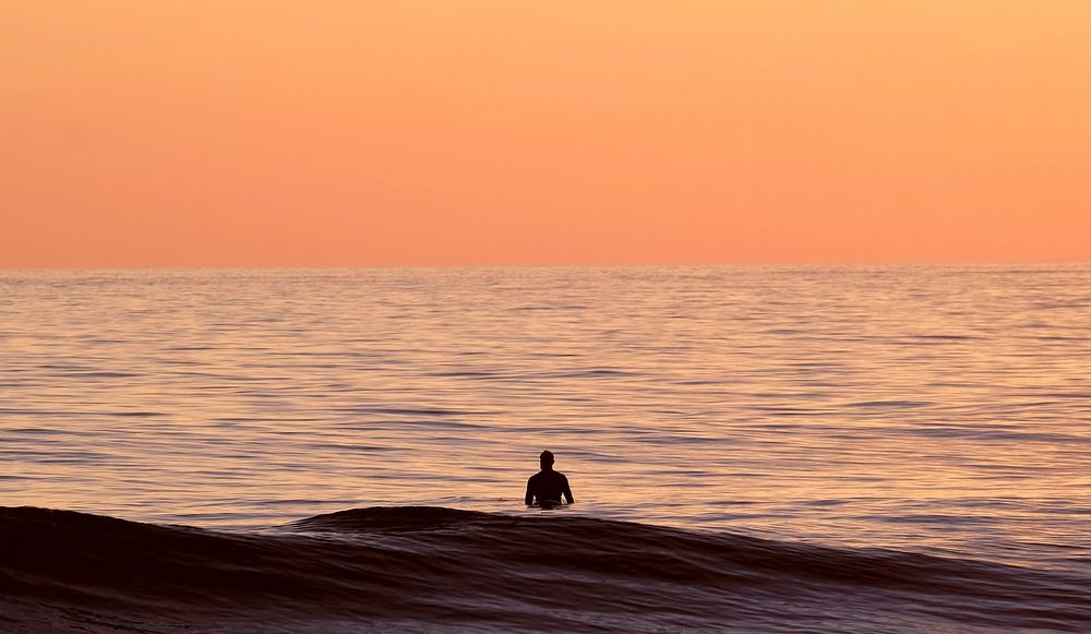 Man staning in ocean sunset. Original public domain image from Wikimedia Commons