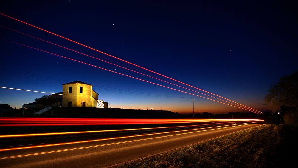 A gleaming red light trail shining down a dark road in Victoria. Original public domain image from Wikimedia Commons