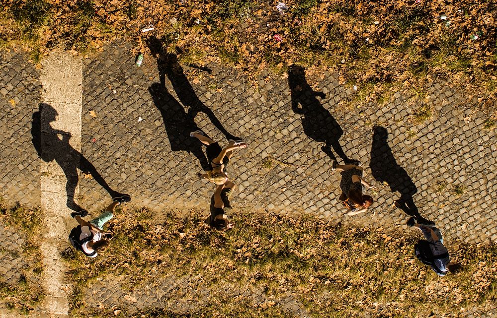 A drone view of people and their shadows walking on a cobblestone pathway. Original public domain image from Wikimedia…