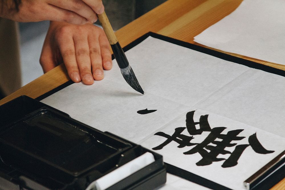 A close-up of a person practicing brush calligraphy.. Original public domain image from Wikimedia Commons