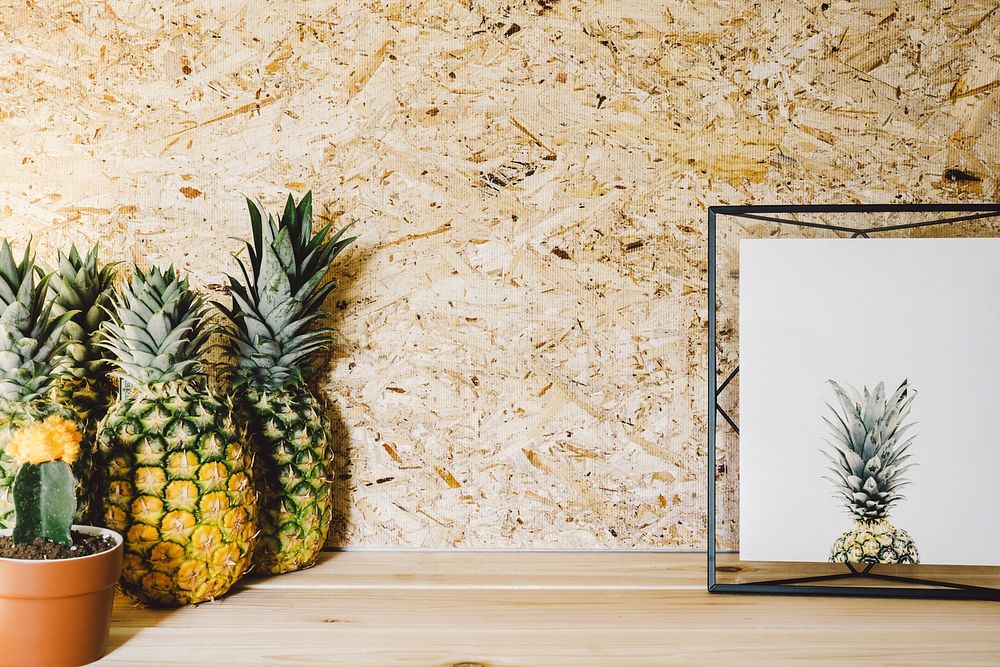 A group of pineapples next to a cactus plant and picture frame.. Original public domain image from Wikimedia Commons