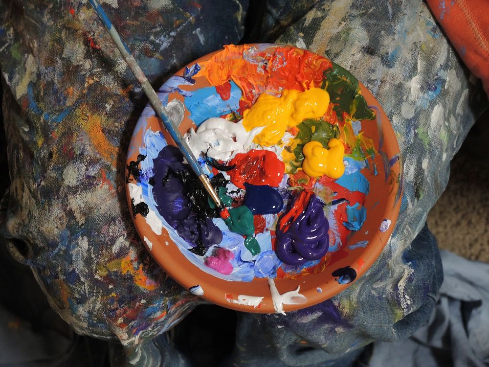 Mix of paints in a orange bowl with paintbrush sit on a messy background. Original public domain image from Wikimedia Commons