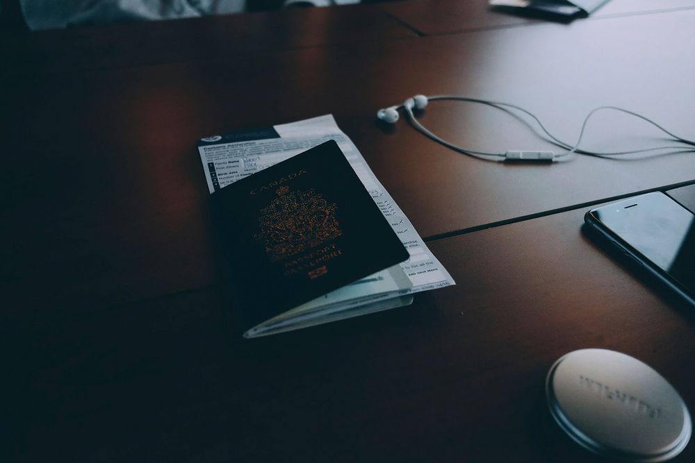 Passport and documents on desk near phone and earphones. Original public domain image from Wikimedia Commons