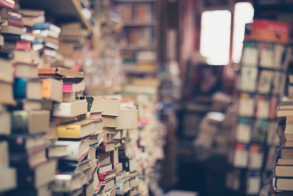 Bookshop with stacks and stacks of old books on the perimeter of the walls. Original public domain image from Wikimedia…