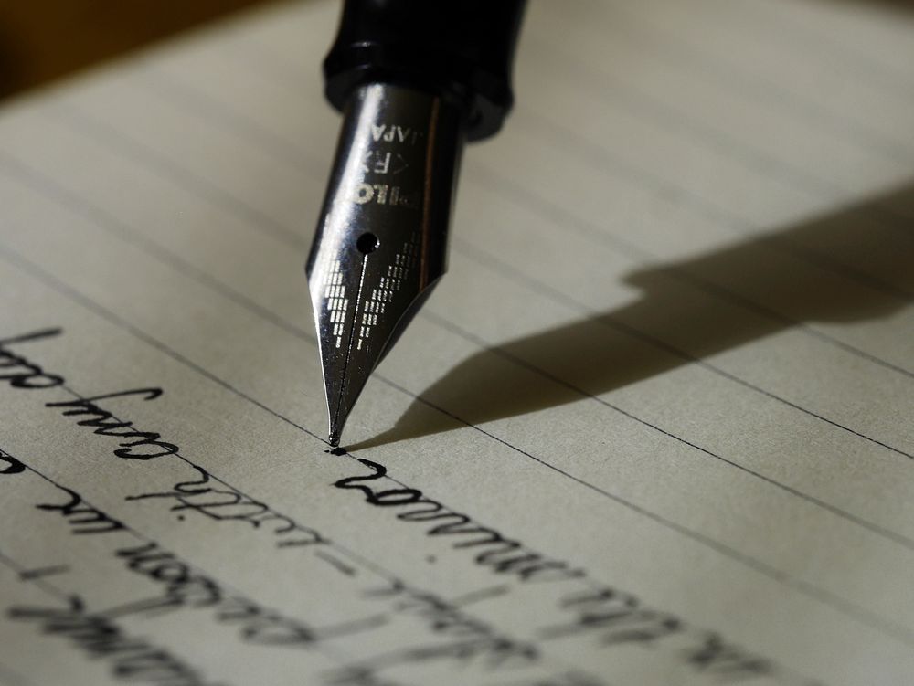 Close-up of a fountain pen writing in a notebook. Original public domain image from Wikimedia Commons