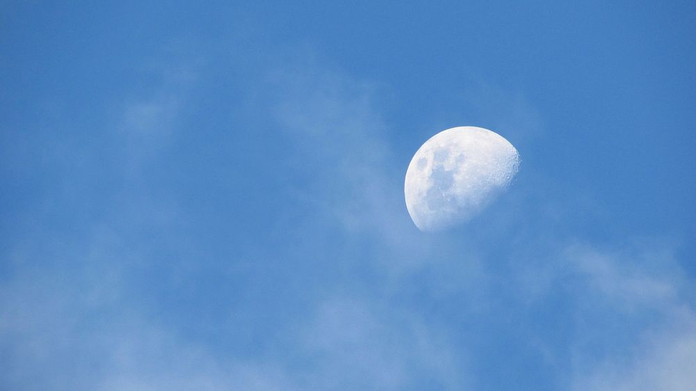 The moon on cloudy blue sky photography. Original public domain image from Wikimedia Commons