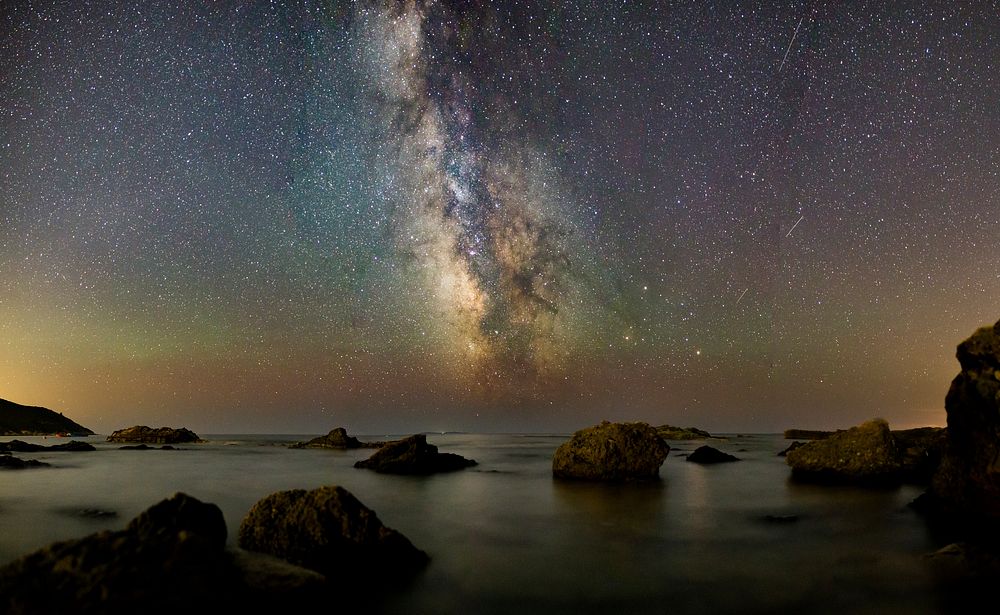Galaxy, starry beach night, rocks. Original public domain image from Wikimedia Commons