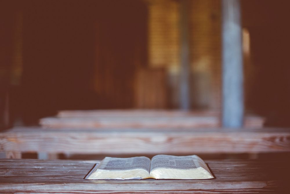 Religious text open on an empty chapel pew. Original public domain image from Wikimedia Commons