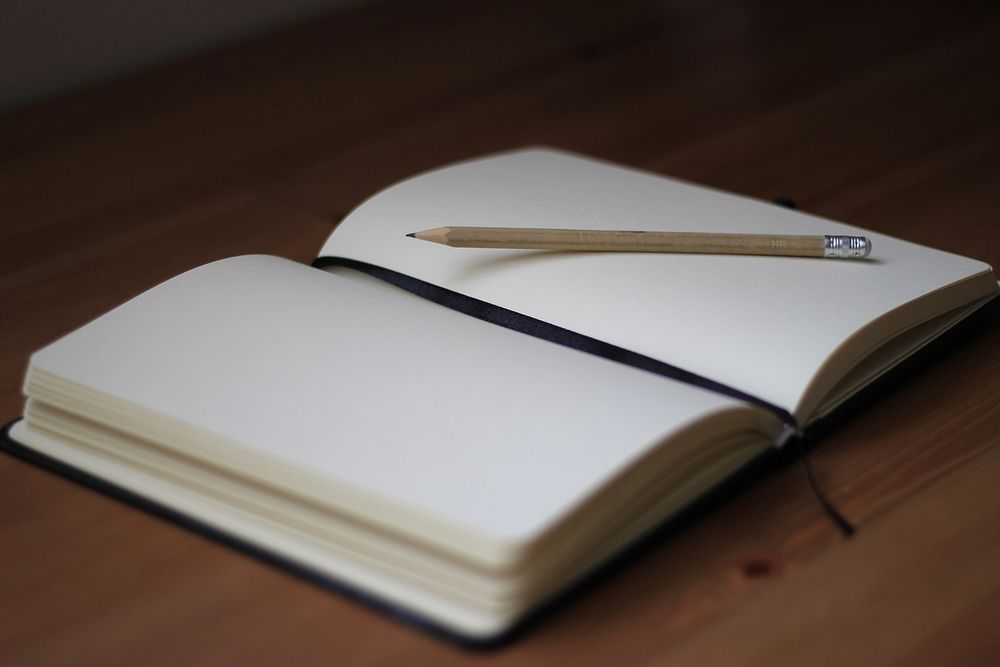 A pencil on the blank pages of an open notebook. Original public domain image from Wikimedia Commons