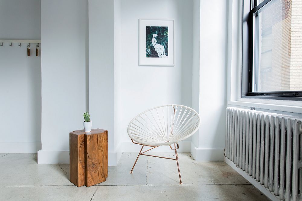 White chair and wood table sit inside a white room next to window. Original public domain image from Wikimedia Commons