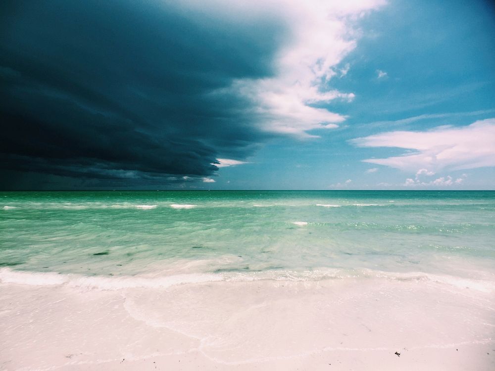 White sandy clear beach, cloudy sky. Original public domain image from Wikimedia Commons