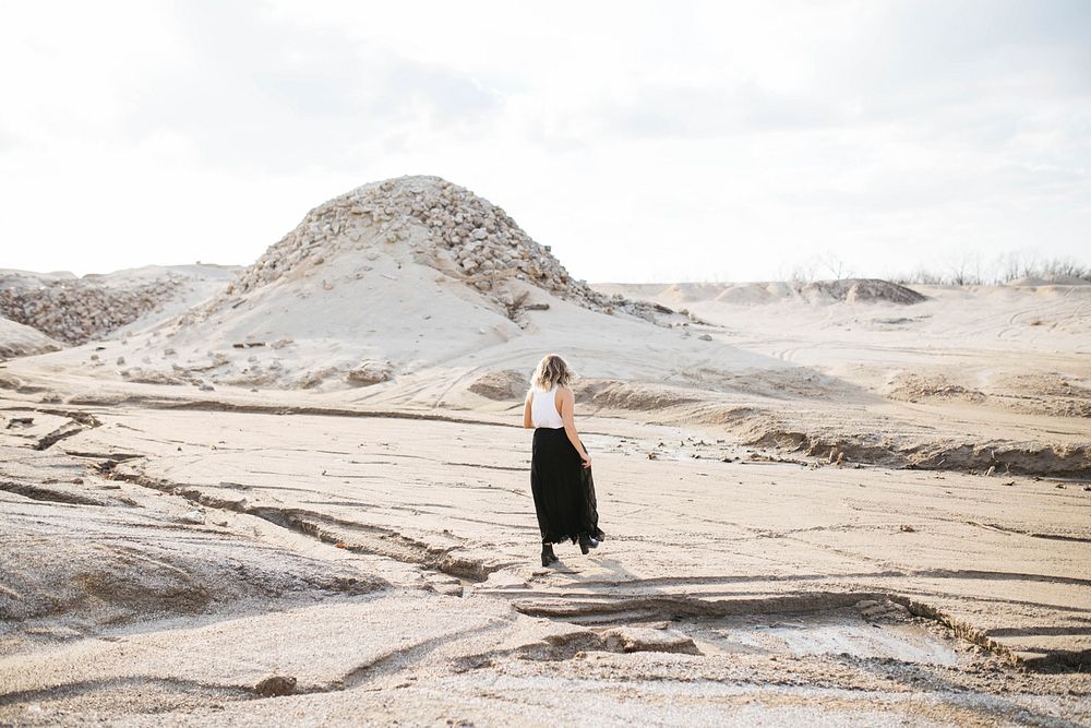 Fashionable woman walks alone through dry desert terrain. Original public domain image from Wikimedia Commons