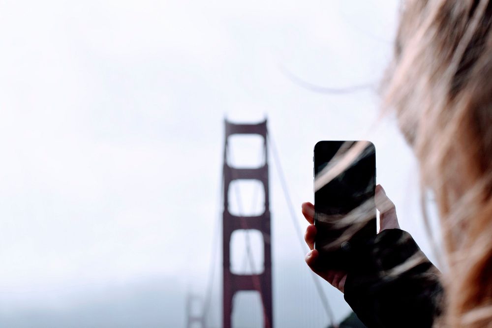 Woman taking a photo of a Golden Gate Bridge in San Francisco, United States. Original public domain image from Wikimedia…