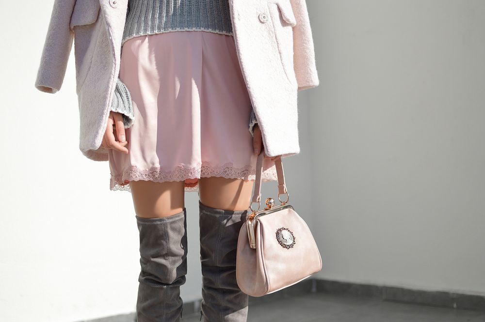 A woman in a pink skirt, long boots and a jacket carrying a pink handbag. Original public domain image from Wikimedia Commons