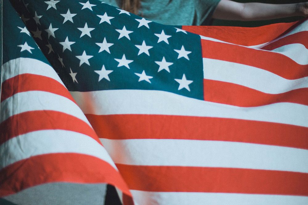 A person holding an American flag. Original public domain image from Wikimedia Commons