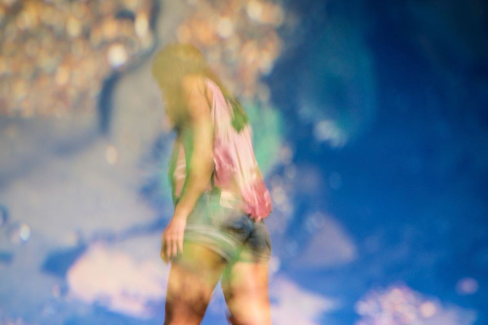 A blurry shot of a woman in shorts against a blue sky. Original public domain image from Wikimedia Commons