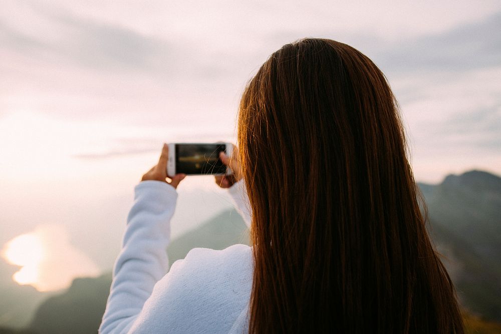 A woman taking a photo of the ocean view. Original public domain image from Wikimedia Commons