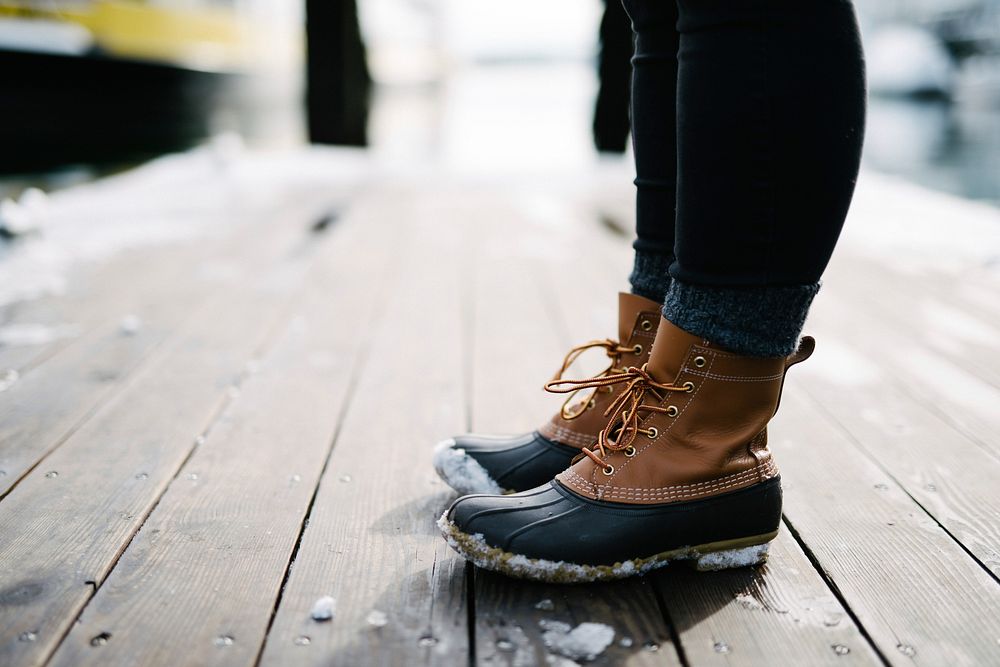 Brown winter boots covered in snow are standing on a wooden floor. Original public domain image from Wikimedia Commons