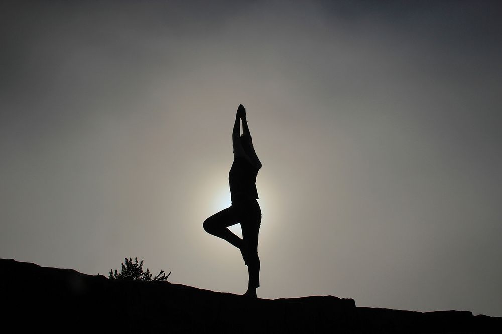 A woman doing yoga on a sloping ground in silhouette. Original public domain image from Wikimedia Commons