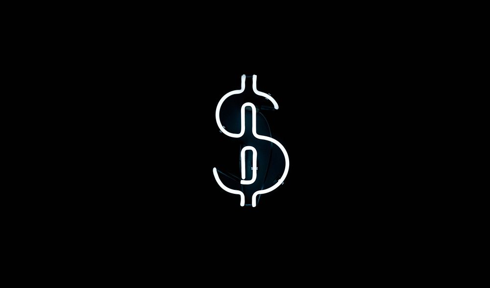 A white neon in the shape of the dollar sign at night. Original public domain image from Wikimedia Commons