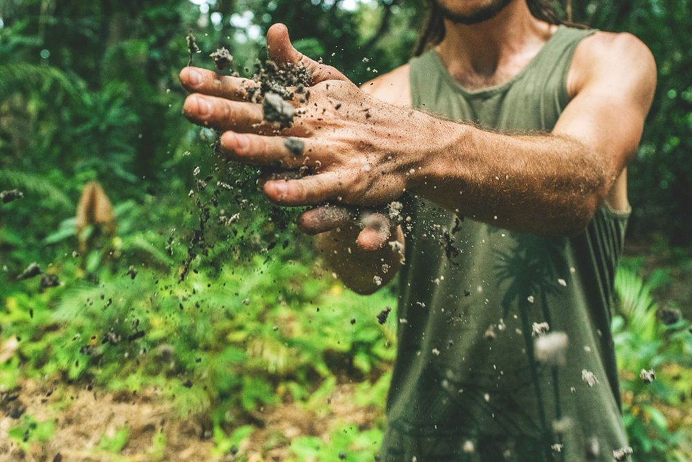 A man wiping dirt off of his hands in the jungle. Original public domain image from Wikimedia Commons