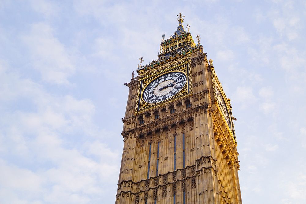 Big Ben clock tower in London with a blue sky and white clouds. Original public domain image from Wikimedia Commons