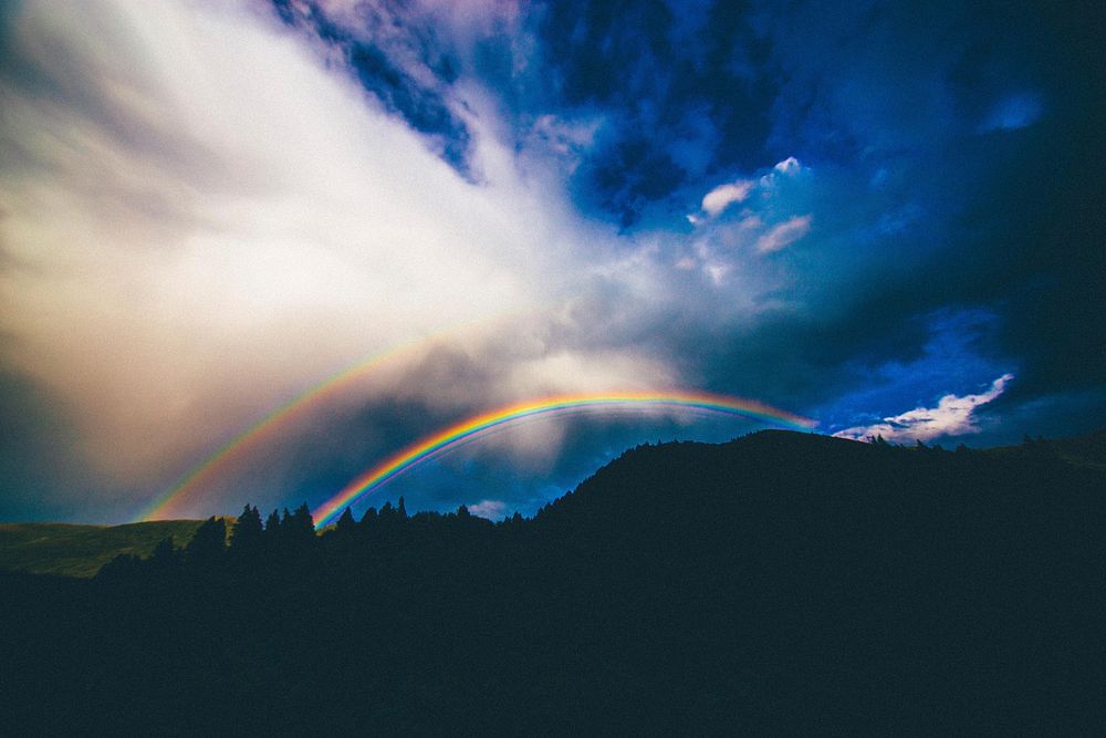 A mountain silhouette with a double rainbow in the blue sky in Provo. Original public domain image from Wikimedia Commons