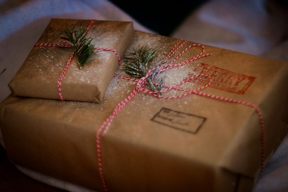 Christmas gift parcels wrapped in brown paper and decorated with twine and pine leaves.. Original public domain image from…