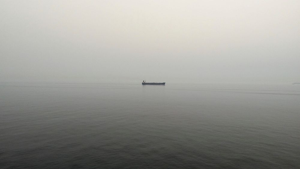 Boat alone on calm gray waters on an overcast foggy morning. Original public domain image from Wikimedia Commons