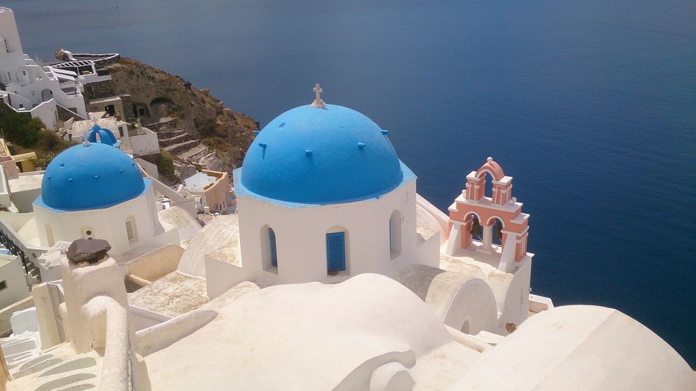 Blue and white rooftops of classic Greek buildings on the seashore. Original public domain image from Wikimedia Commons