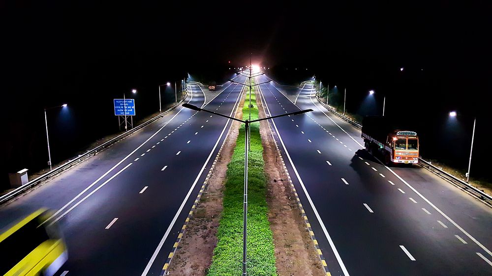 A relatively empty dual highway illuminated by artificial light at night. Original public domain image from Wikimedia Commons
