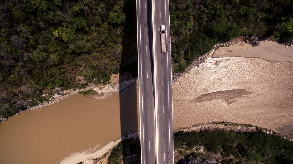 An aerial shot of a truck on a bridge over a muddy river. Original public domain image from Wikimedia Commons