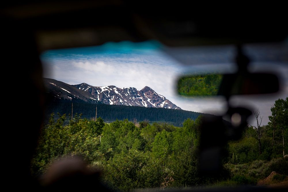 View of snow covered mountains and forest seen through car windshield. Original public domain image from Wikimedia Commons