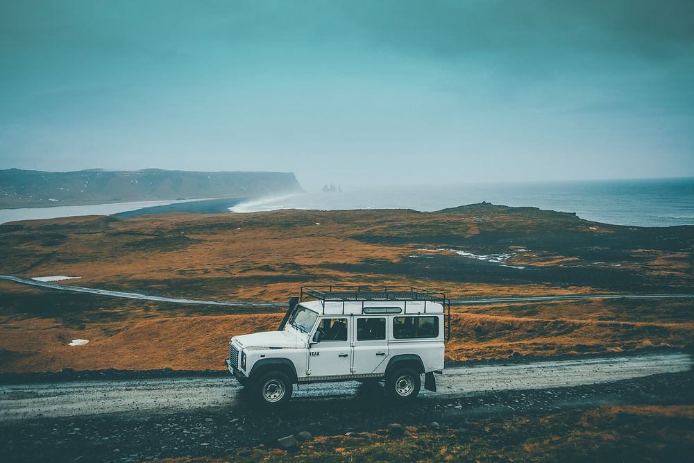 A white off-road vehicle on a dirt road with a misty shoreline at the back. Original public domain image from Wikimedia…