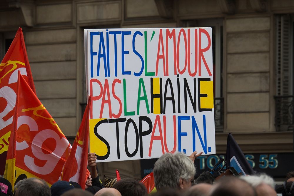 A protest sign in Paris reads "faites l'amour pas la haine stop au fn". Original public domain image from Wikimedia Commons