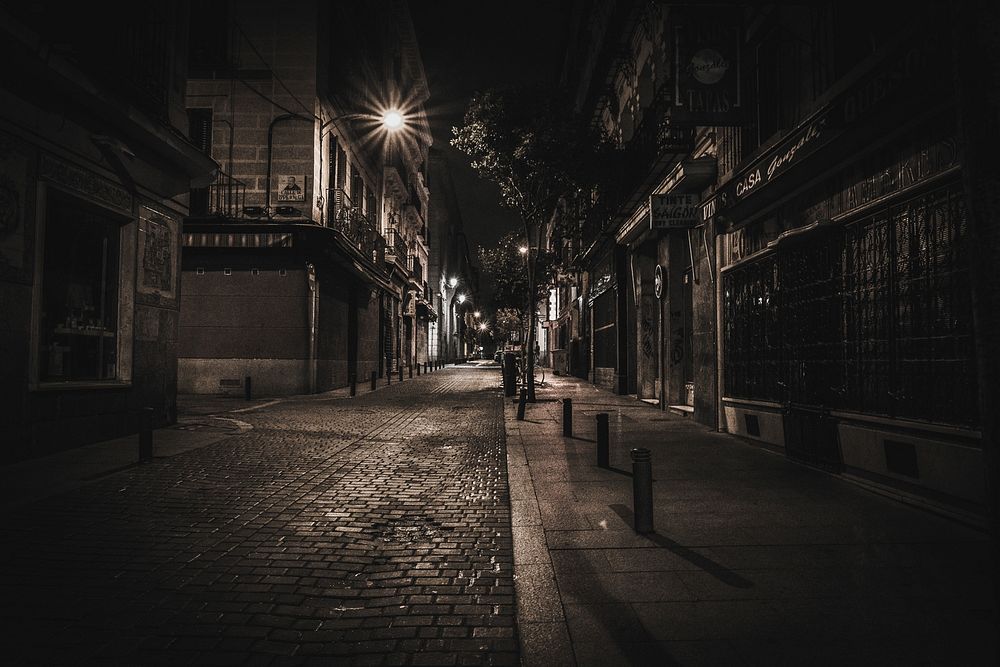 Narrow, cobblestone street at night with street lamps illuminating the road. Original public domain image from Wikimedia…