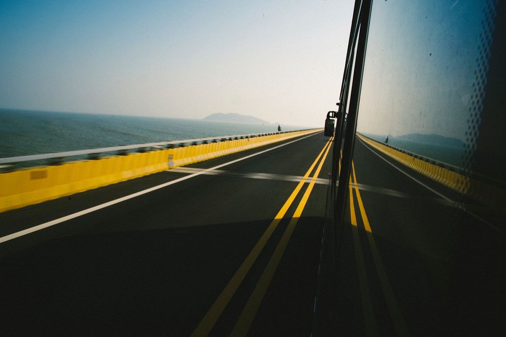 Vehicle running on the bridge road with sea view. Original public domain image from Wikimedia Commons