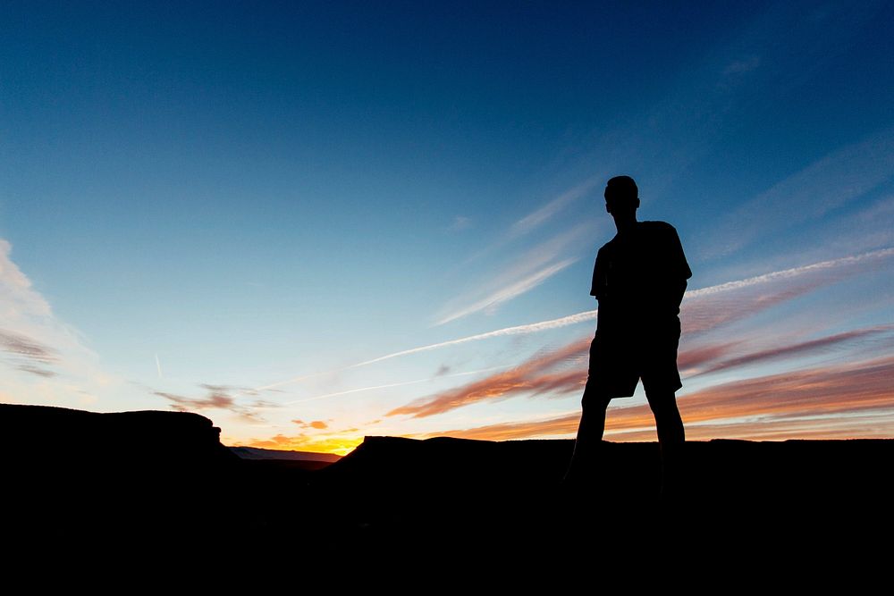 Male silhouette in the late evening sunset under a mostly clear sky. Original public domain image from Wikimedia Commons