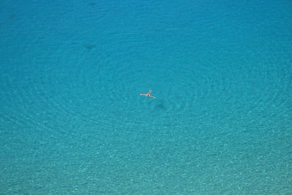 Aerial photo of person swimming on body in the blue clear sea during daytime. Original public domain image from Wikimedia…