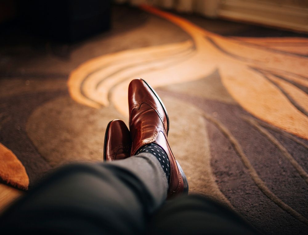 A man wearing a pair of brown leather shoes lying on the floor mat. Original public domain image from Wikimedia Commons