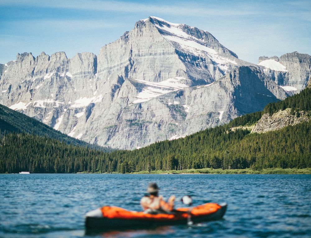A person kayaking by the mountains in Swiftcurrent Lake. Original public domain image from Wikimedia Commons