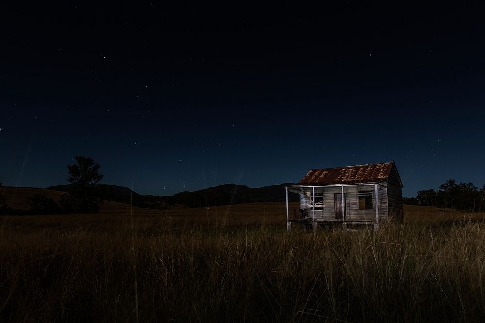 Abandoned house in a field at night. Original public domain image from Wikimedia Commons