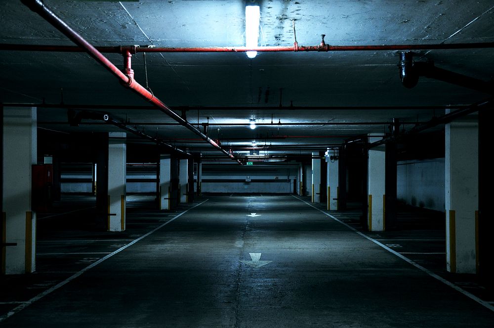 An underground empty urban industrial dark parking lot with fluorescent light over it in landmark place. Original public…