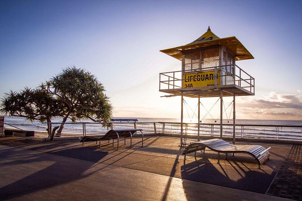 Lifeguard stand and tree cast shadows on the beach side promenade at Surfers Paradise during sunrise-or-sunset. Original…