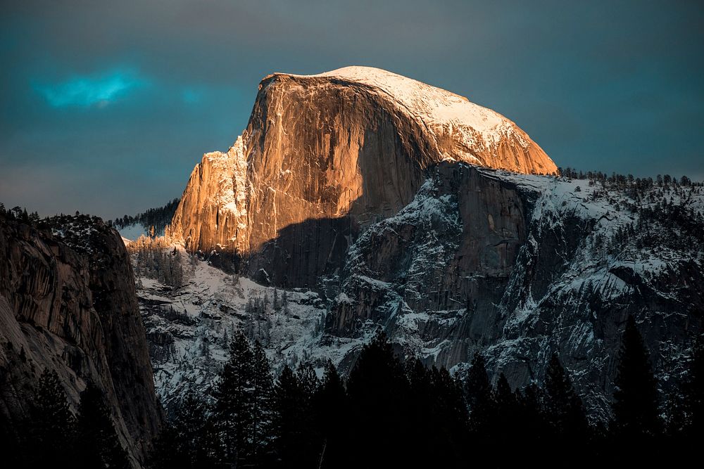 The sun lighting up a snowcapped Half Dome peak at California's Yosemite National Park. Original public domain image from…