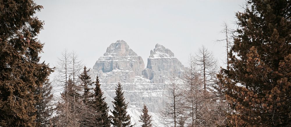 A wintry landscape with evergreen trees and two sharp mountain peaks near Lake Misurina. Original public domain image from…