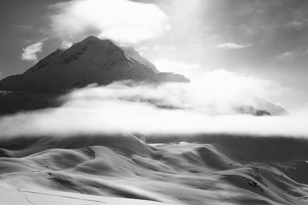Black and white shot of sand with clouds, mountain peak and sun, Les Arcs. Original public domain image from Wikimedia…