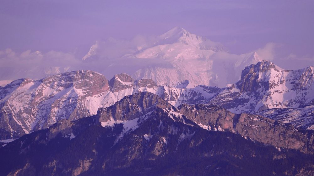 A purple-hued shot of the mighty Mont Blanc towering over granite ridges. Original public domain image from Wikimedia Commons